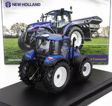 Modèle réduit de tracteur bleu New Holland moulé sous pression, présenté sur un socle noir avec un emballage représentant le tracteur réel dans un champ, disponible chez Vroomi.
