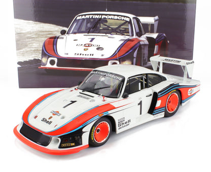 Modèle réduit de voiture de course Porsche Martini blanche avec bandes rouges et bleues, logos des sponsors, présenté avec son emballage, disponible via Vroomi.
