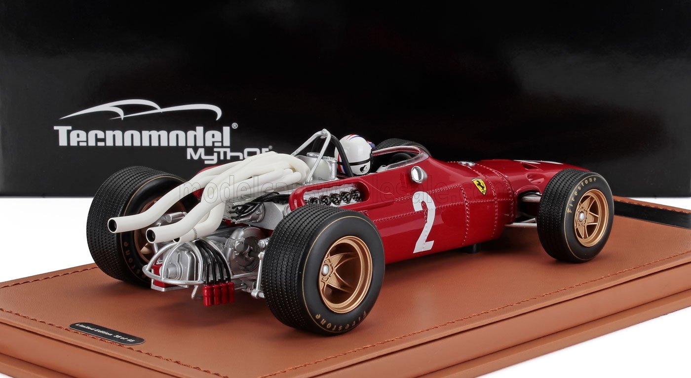 Modèle réduit vintage d'une Ferrari rouge avec le numéro 2, présenté sur un tapis en cuir, disponible sur la plateforme Vroomi.