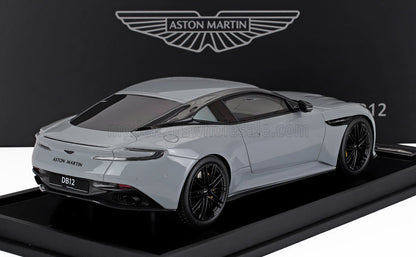 Modèle réduit Aston Martin DB12 gris avec accents carbone noir présenté sur un socle noir, disponible sur Vroomi.