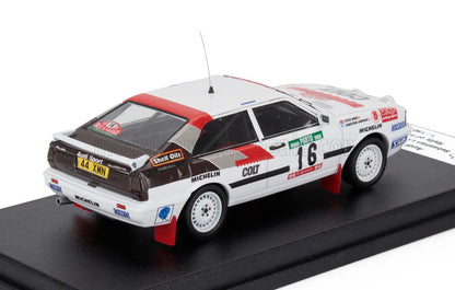 Modèle détaillé d'une voiture de rallye Audi Sport Quattro blanche avec des accents rouges et noirs, numéro 16, présenté sur un socle noir, proposé sur Vroomi.
