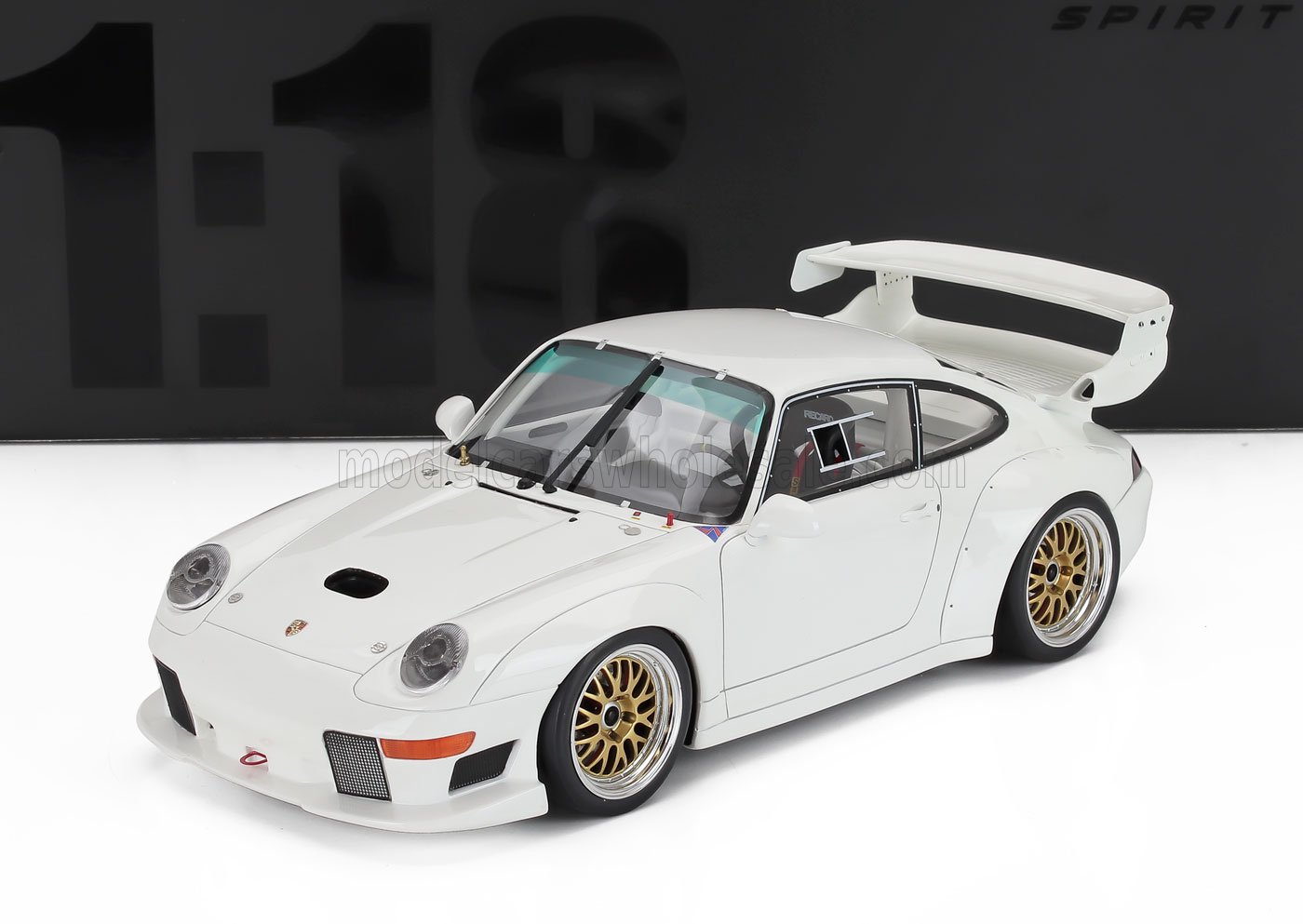 Modèle réduit Porsche 911 blanc à l'échelle 1:18 avec jantes dorées et grand aileron arrière, disponible chez Vroomi.