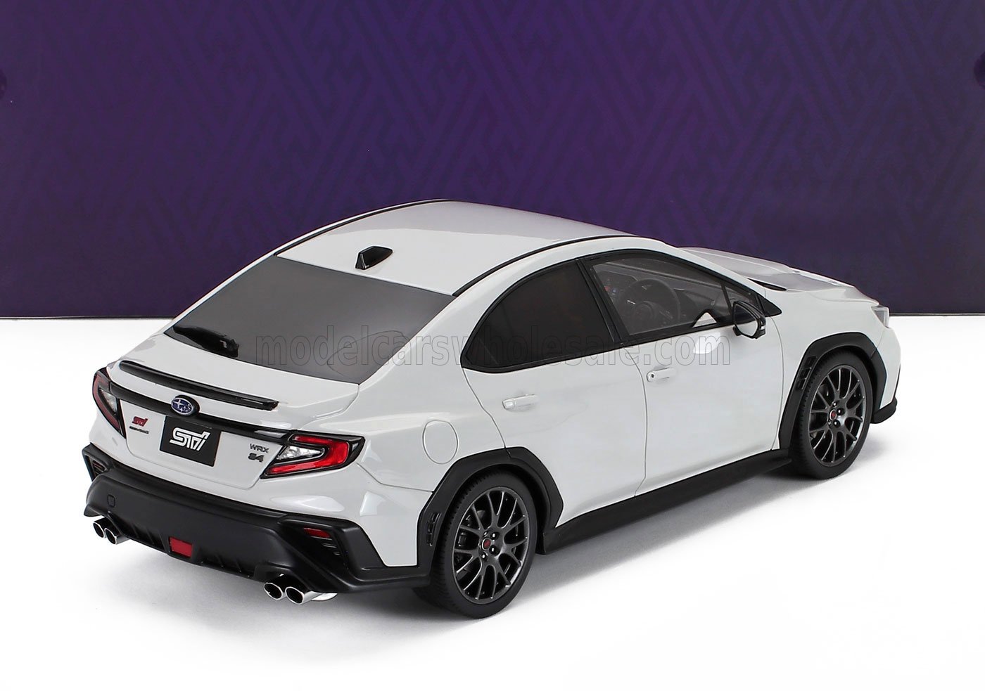 Modèle réduit de voiture Subaru WRX STI blanche à l'échelle 1/18 avec roues noires, disponible chez Vroomi.
