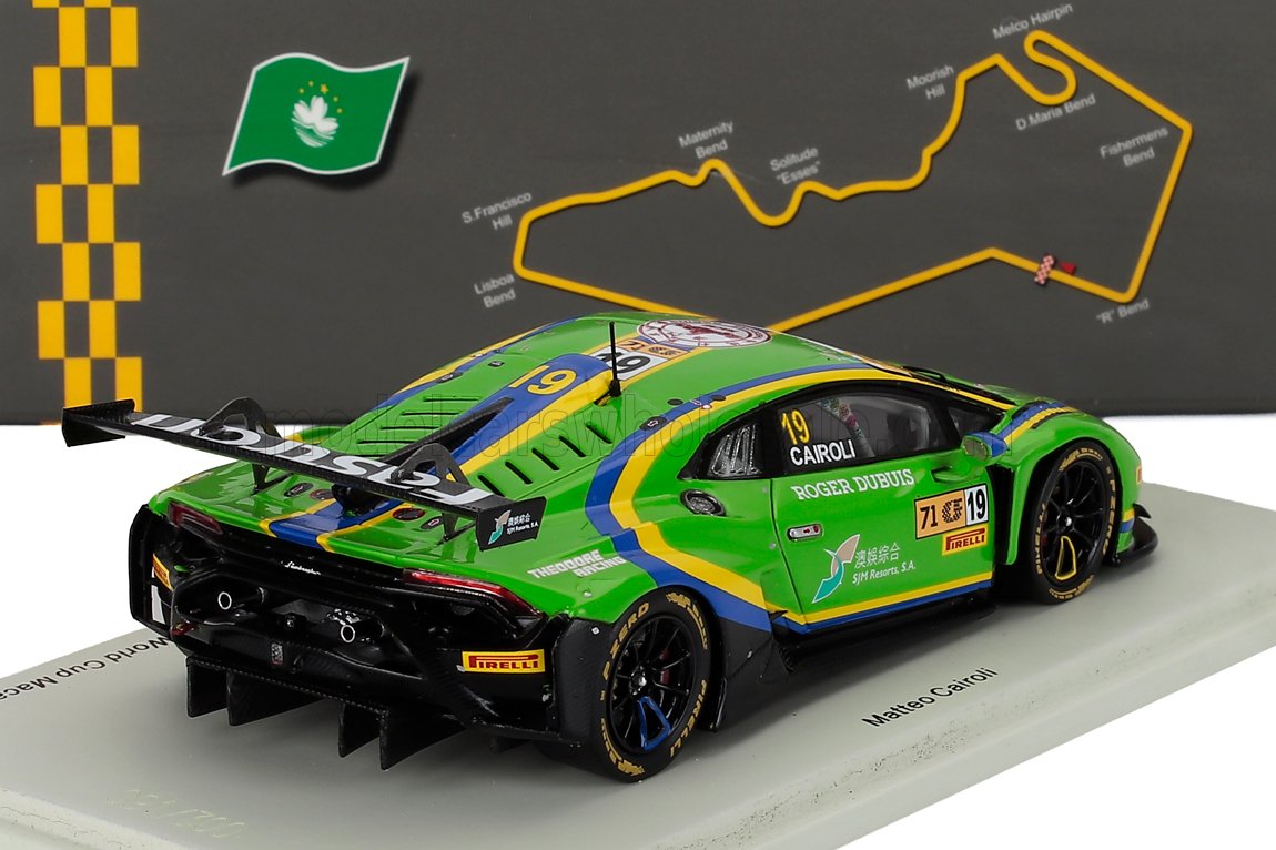 Modèle réduit de voiture de course Lamborghini Huracán GT3 à l'échelle 1/18, vert et bleu, avec décalcomanies de course, présenté sur un socle blanc avec le circuit de Macao en arrière-plan, disponible chez Vroomi.