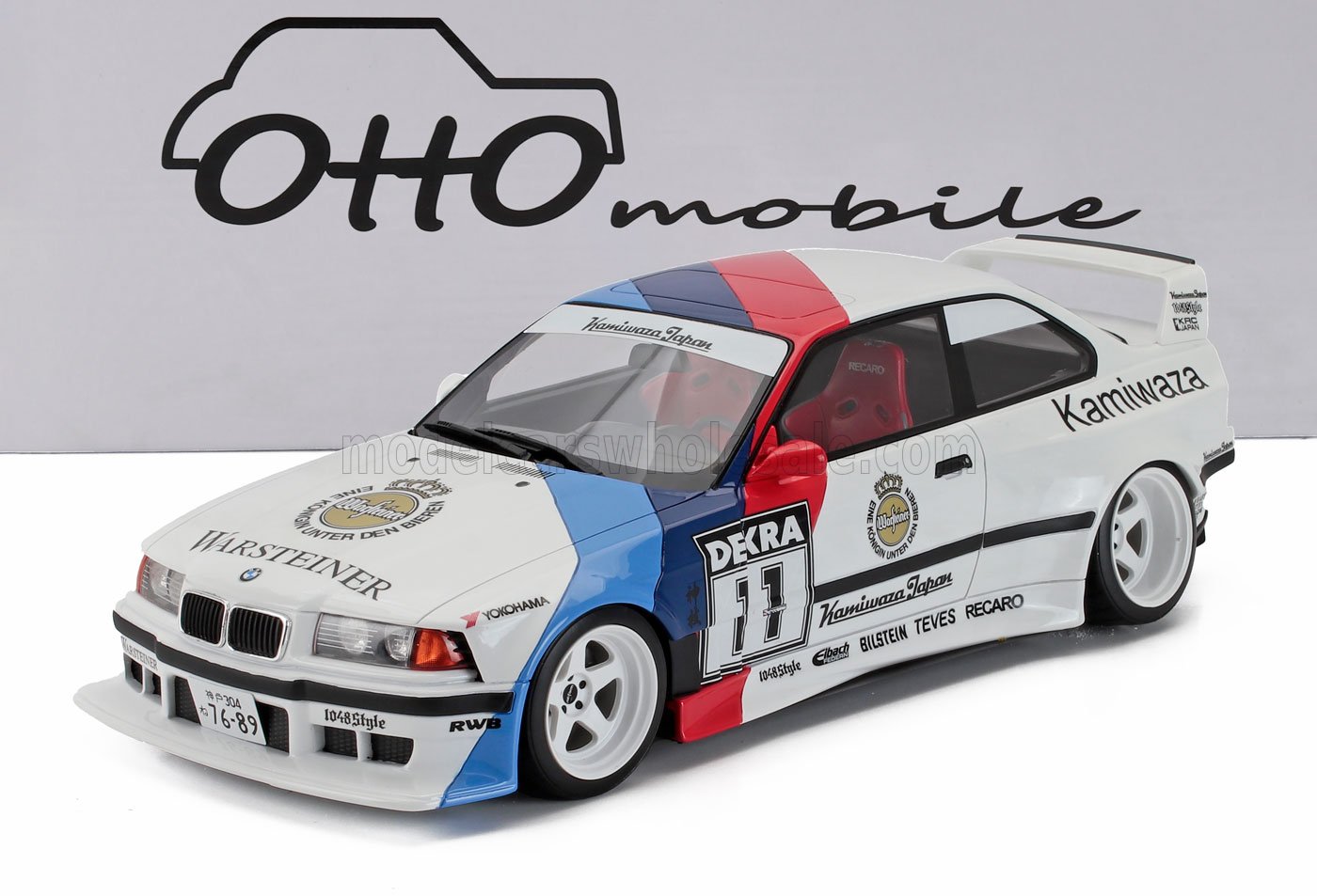 Modèle réduit de voiture de course BMW blanche avec décalcomanies rouges et bleues, sièges Recaro et logos des sponsors, disponible sur Vroomi.