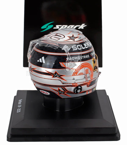 Casque de course miniature à l'échelle 1/5 avec motif étoilé argenté, noir et orange et logos des sponsors sur socle d'exposition, disponible chez Vroomi.