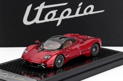 Modèle réduit de voiture Pagani Utopia rouge sur socle noir, caractérisé par des courbes élégantes et des roues détaillées, disponible via Vroomi.