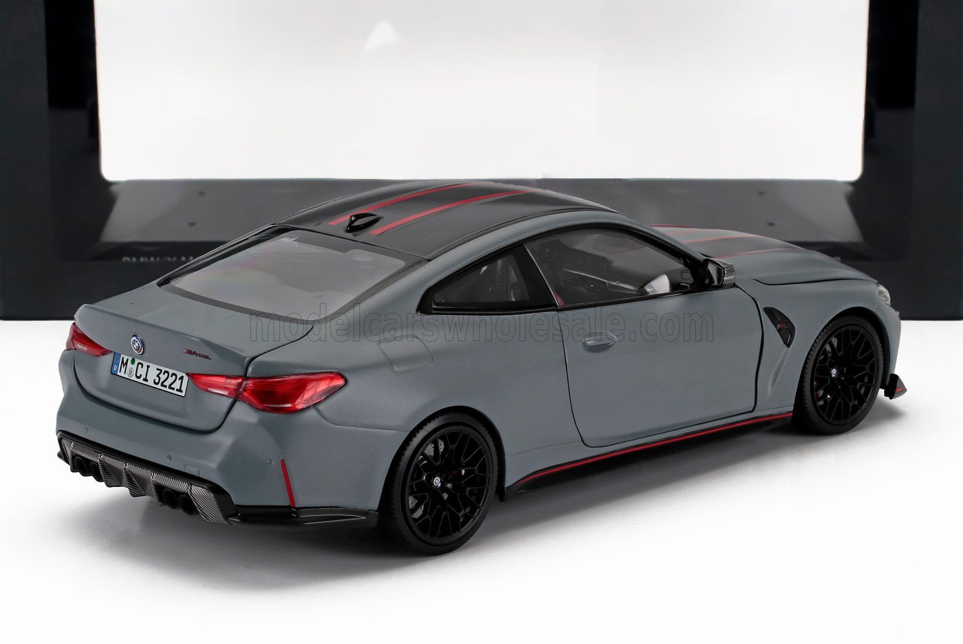 Modèle réduit BMW M4 gris mat avec jantes noires et bandes rouges, également disponible sur Vroomi.