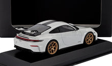 Modèle réduit Porsche 911 GT3 blanc avec bande noire et jantes dorées, présenté sur un socle noir, disponible chez Vroomi.
