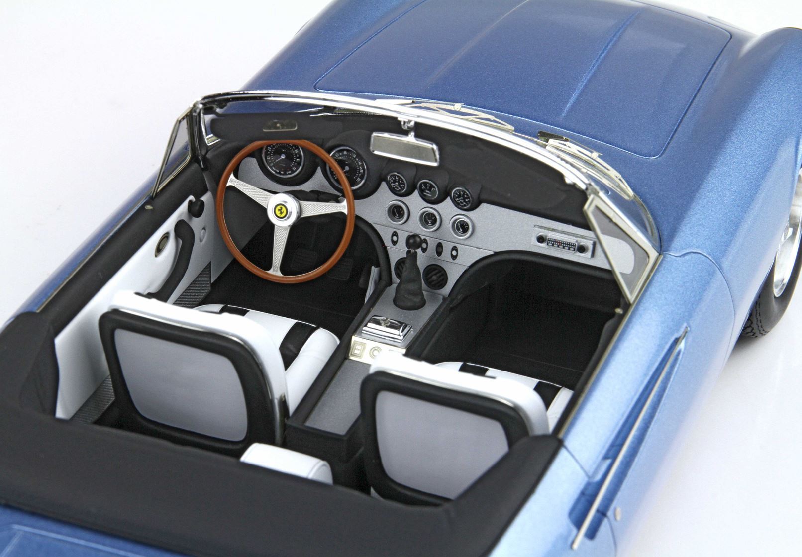 Blue vintage Ferrari convertible interior with wooden steering wheel and white leather seats, available on Vroomi