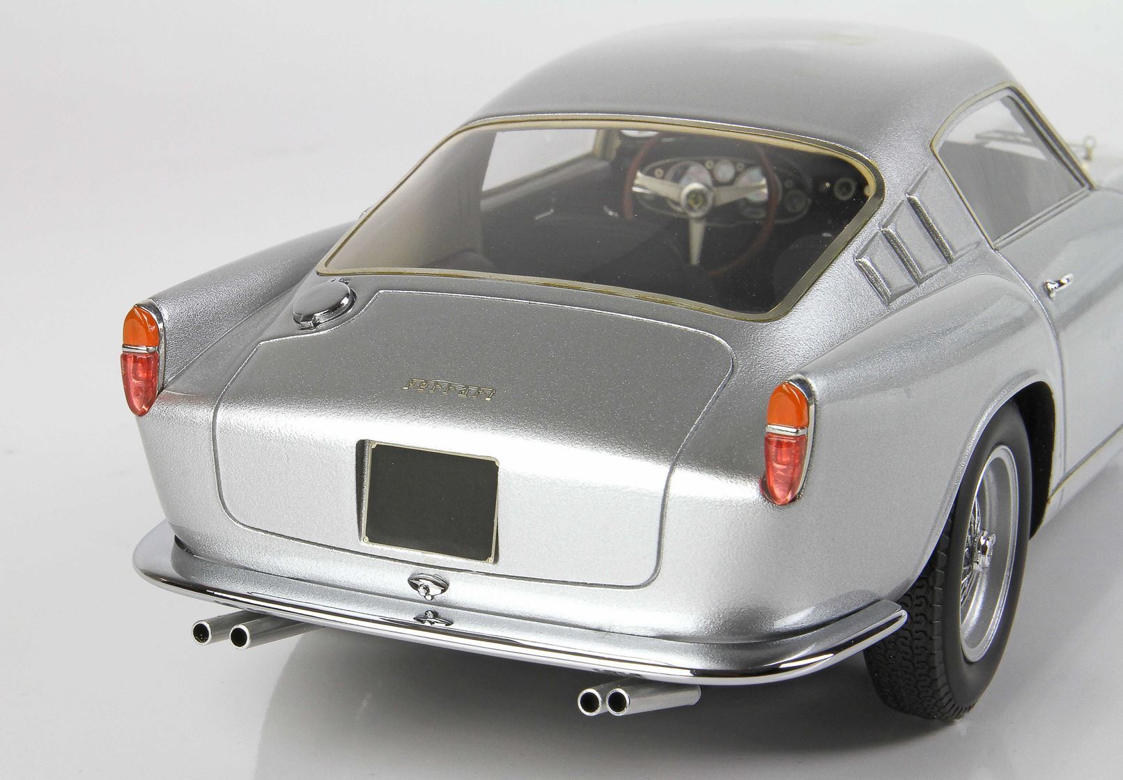 Silver classic Ferrari model car rear view with orange tail lights and dual exhaust, offered on Vroomi