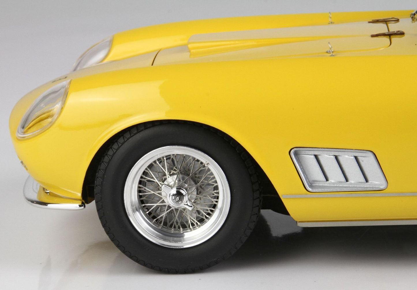 Gros plan sur la roue avant jaune d'une voiture classique avec jante à rayons métalliques, disponible sur la plateforme Vroomi.