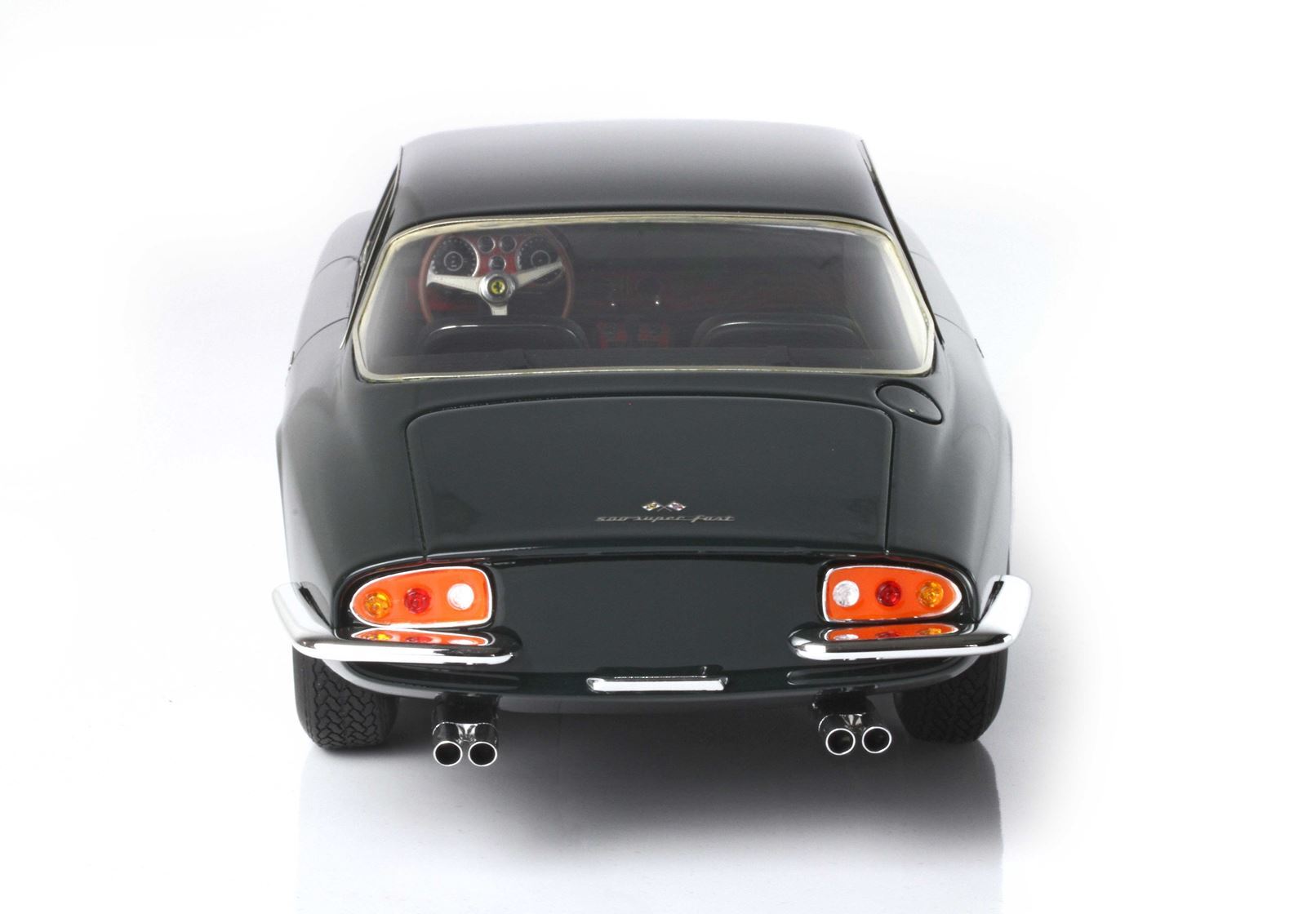 Rear view of a classic dark green sports car with dual exhausts, detailed dashboard visible, available on Vroomi