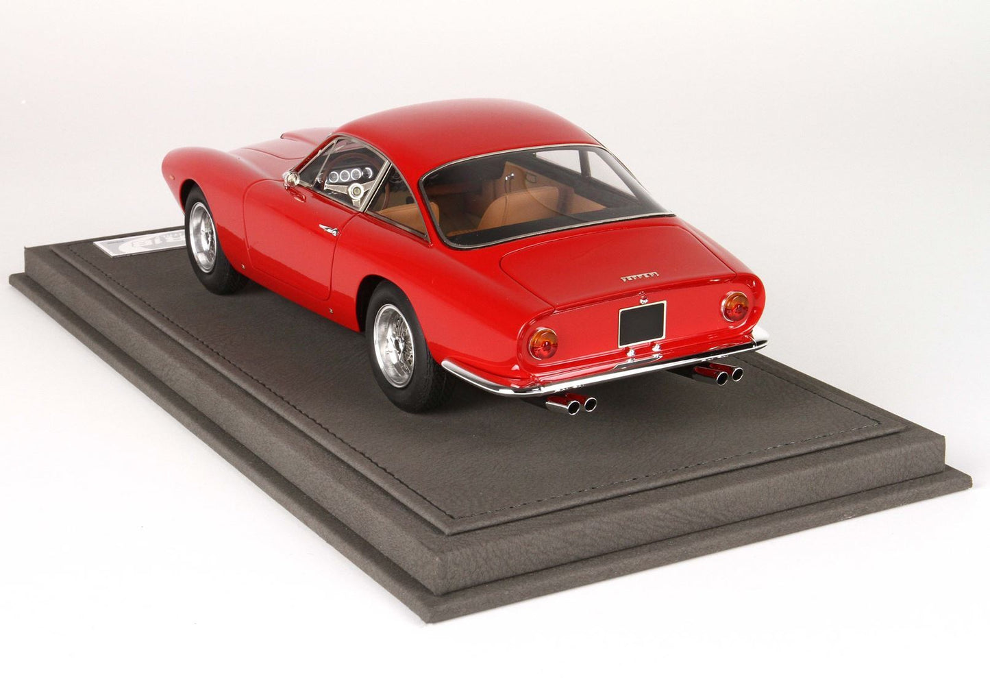 Red vintage Ferrari model car on black display base, features dual exhaust and tan interior, available via Vroomi