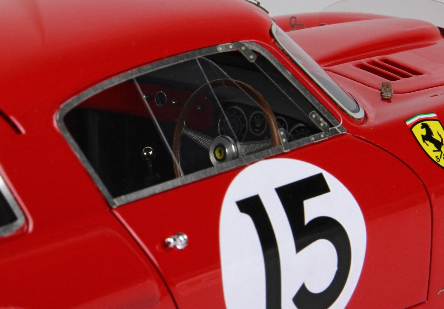 Close-up of red vintage Ferrari race car with number 15 and wooden steering wheel, available on Vroomi