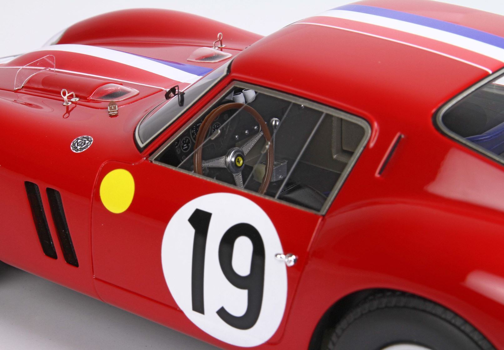 Modèle réduit de voiture de course vintage rouge avec autocollant numéro 19, volant Ferrari, intérieur détaillé, désormais disponible sur Vroomi.