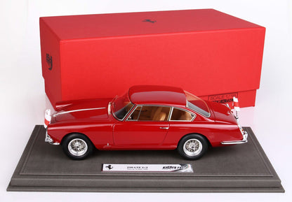 Modèle réduit Ferrari 250 GTE 2+2 à l'échelle 1:18 rouge sur socle d'exposition avec boîte rouge, également proposé sur Vroomi.