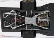 Gros plan sur le dessous d'un modèle réduit de voiture de course montrant le moteur, les tuyaux d'échappement et la suspension arrière en détail, disponible sur Vroomi.