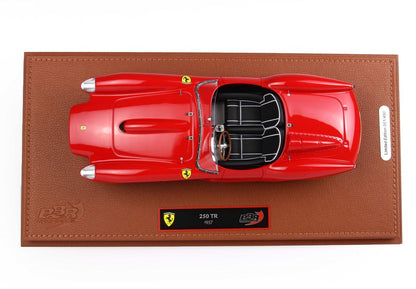 Top view of red 1957 Ferrari 250 TR model on brown leather base with PBR branding, now offered through Vroomi