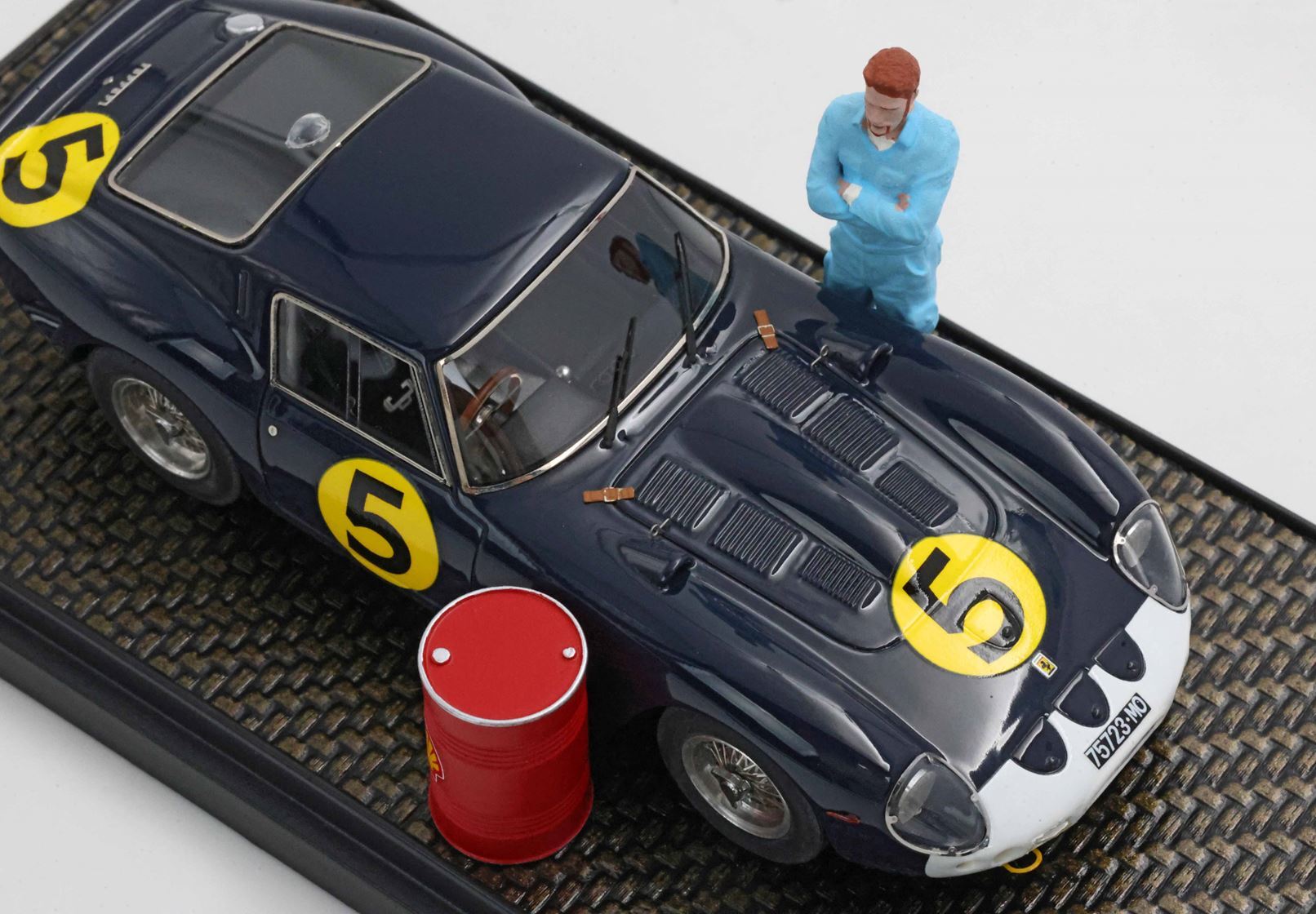 Dark blue vintage race car number 5 with miniature mechanic figure and red barrel, available on Vroomi