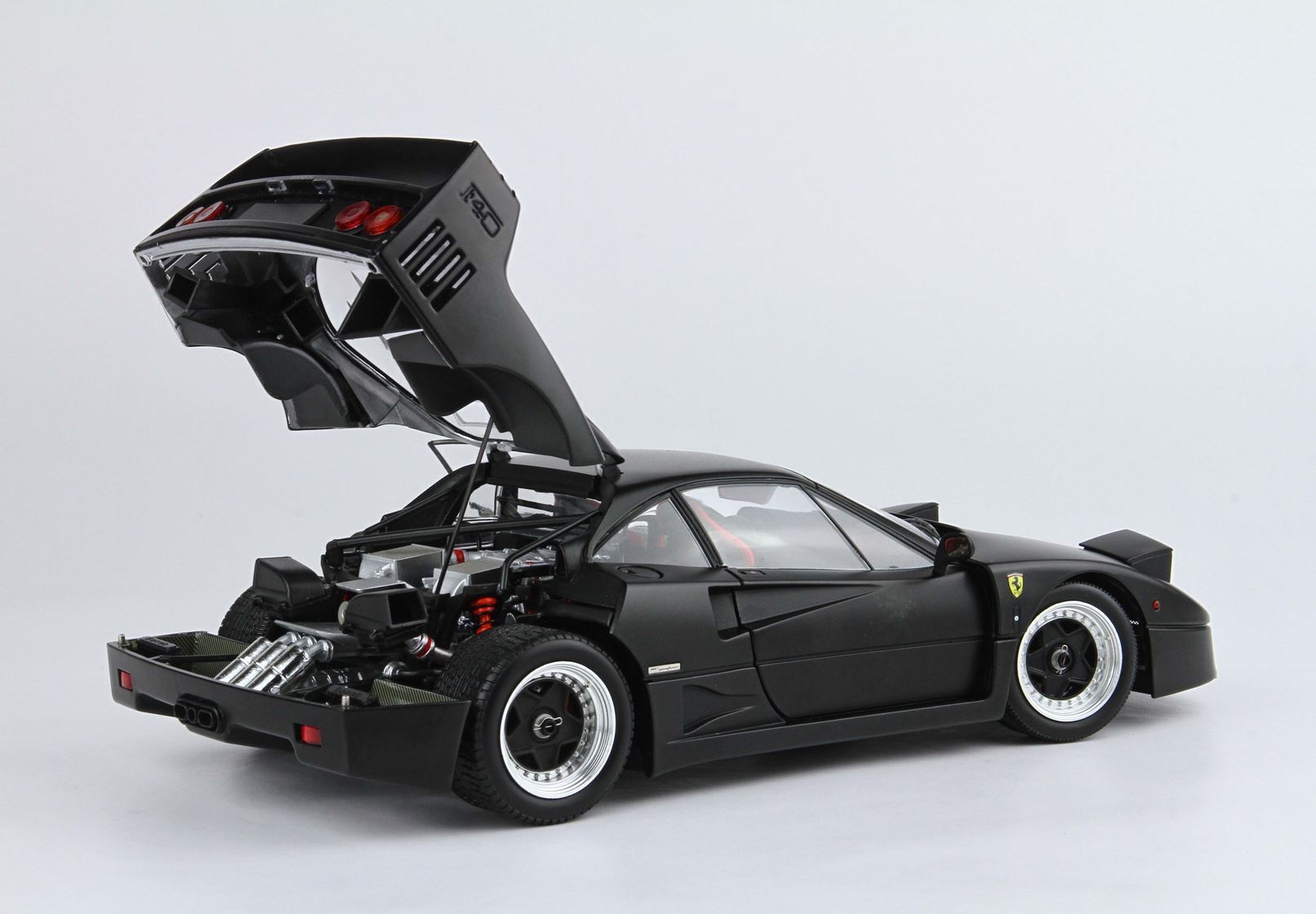 Matte black Ferrari F40 model car with open rear engine bay showcasing detailed components, available on Vroomi