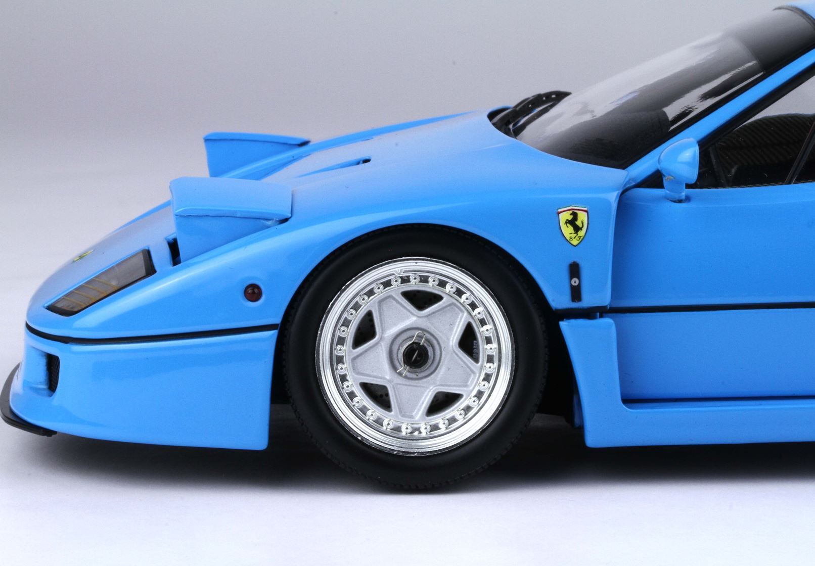 Gros plan sur l'avant d'une maquette de Ferrari bleue avec roues et emblèmes détaillés, disponible via Vroomi.