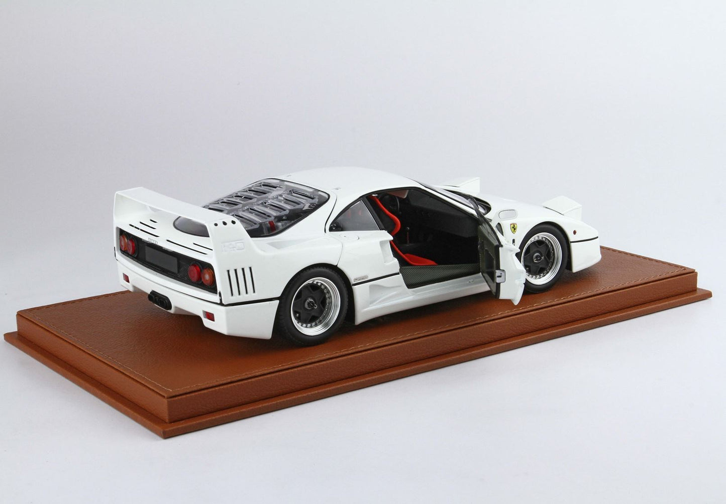 Modèle réduit de Ferrari F40 blanche avec porte ouverte sur socle en cuir marron, disponible sur Vroomi