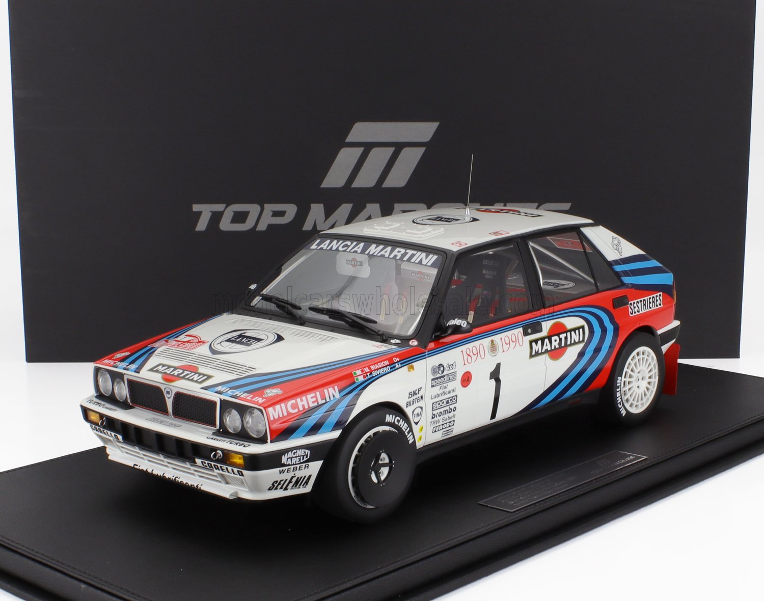 Modello di auto da rally Lancia Delta Martini con adesivi da corsa su piattaforma espositiva, in vendita su Vroomi.