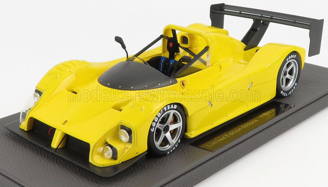 Modellino di auto da corsa Ferrari gialla con pneumatici Goodyear e spoiler posteriore su base espositiva, offerto tramite Vroomi.