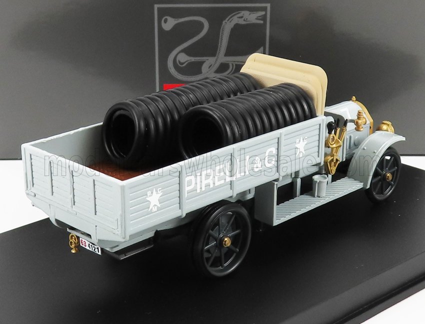 Modello vintage di furgone Pirelli grigio chiaro carico di pneumatici neri in esposizione, ora disponibile su Vroomi.