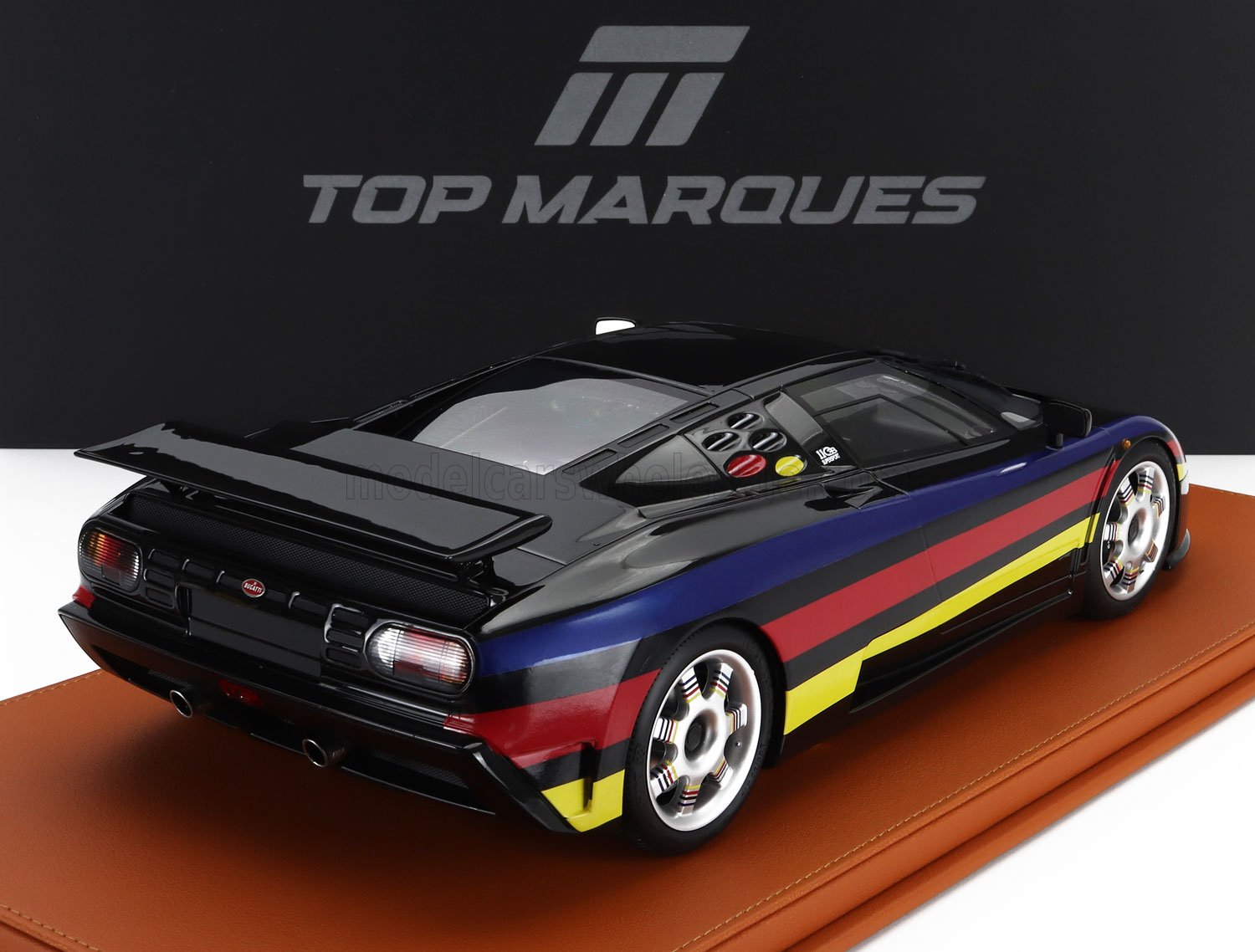 Modello di auto sportiva nera con strisce blu, rosse e gialle su base in pelle, presente su Vroomi.