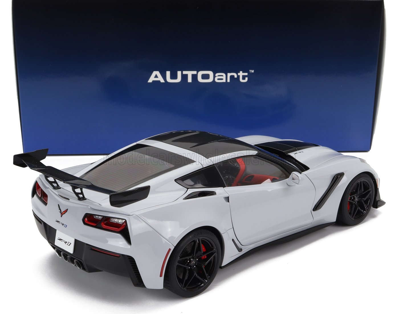 Modellino in scala ridotta di Chevrolet Corvette ZR1 bianca con spoiler nero e interni rossi, disponibile su Vroomi.