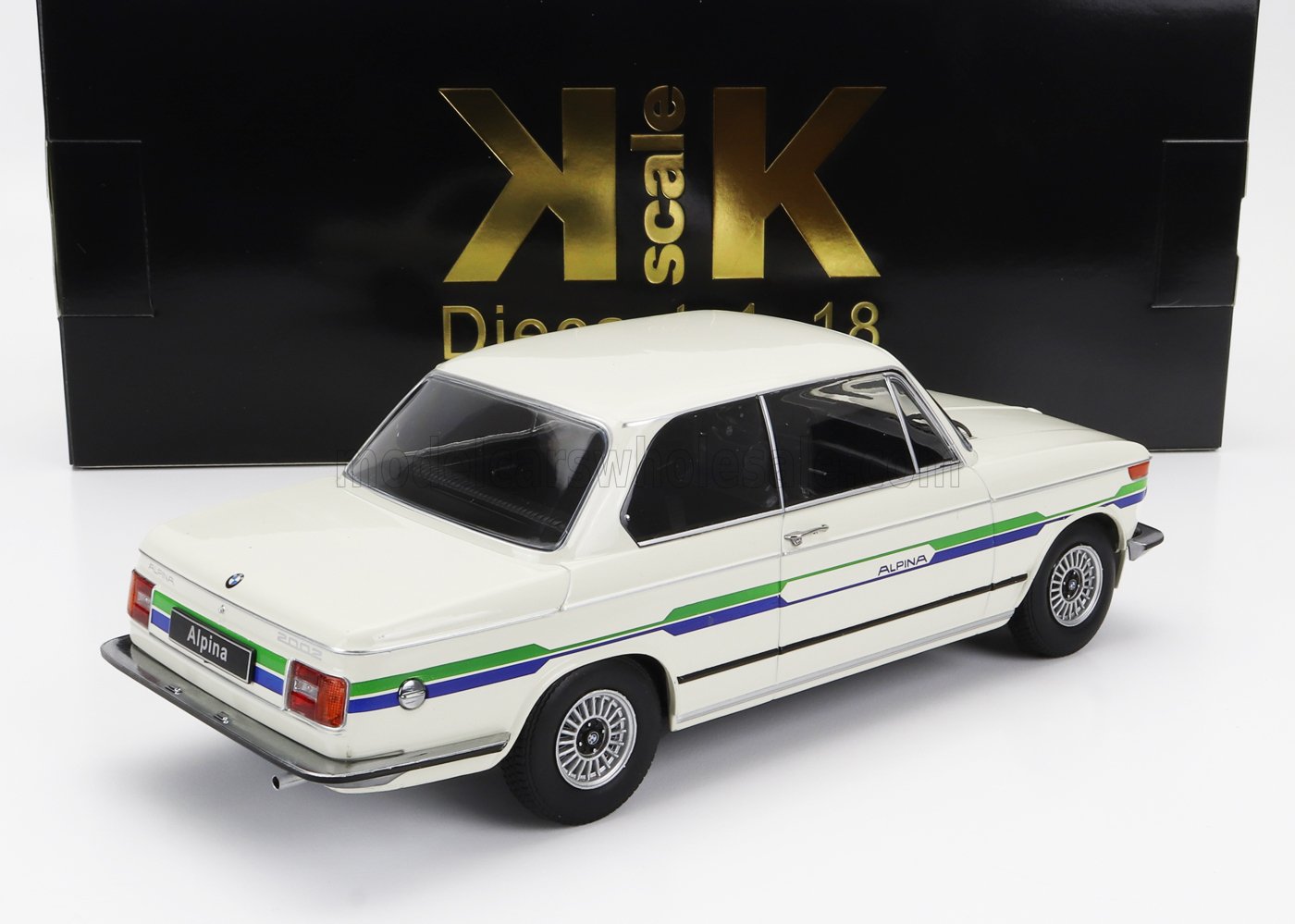 Modellino in scala di una BMW 2002 Alpina bianca con strisce verdi e blu, presentato in una confezione KK Scale nera e dorata, disponibile su Vroomi.