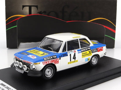 Modello dettagliato dell'auto da corsa BMW 2002 con livrea blu e bianca, adesivi da rally e fari anteriori, ora disponibile su Vroomi.