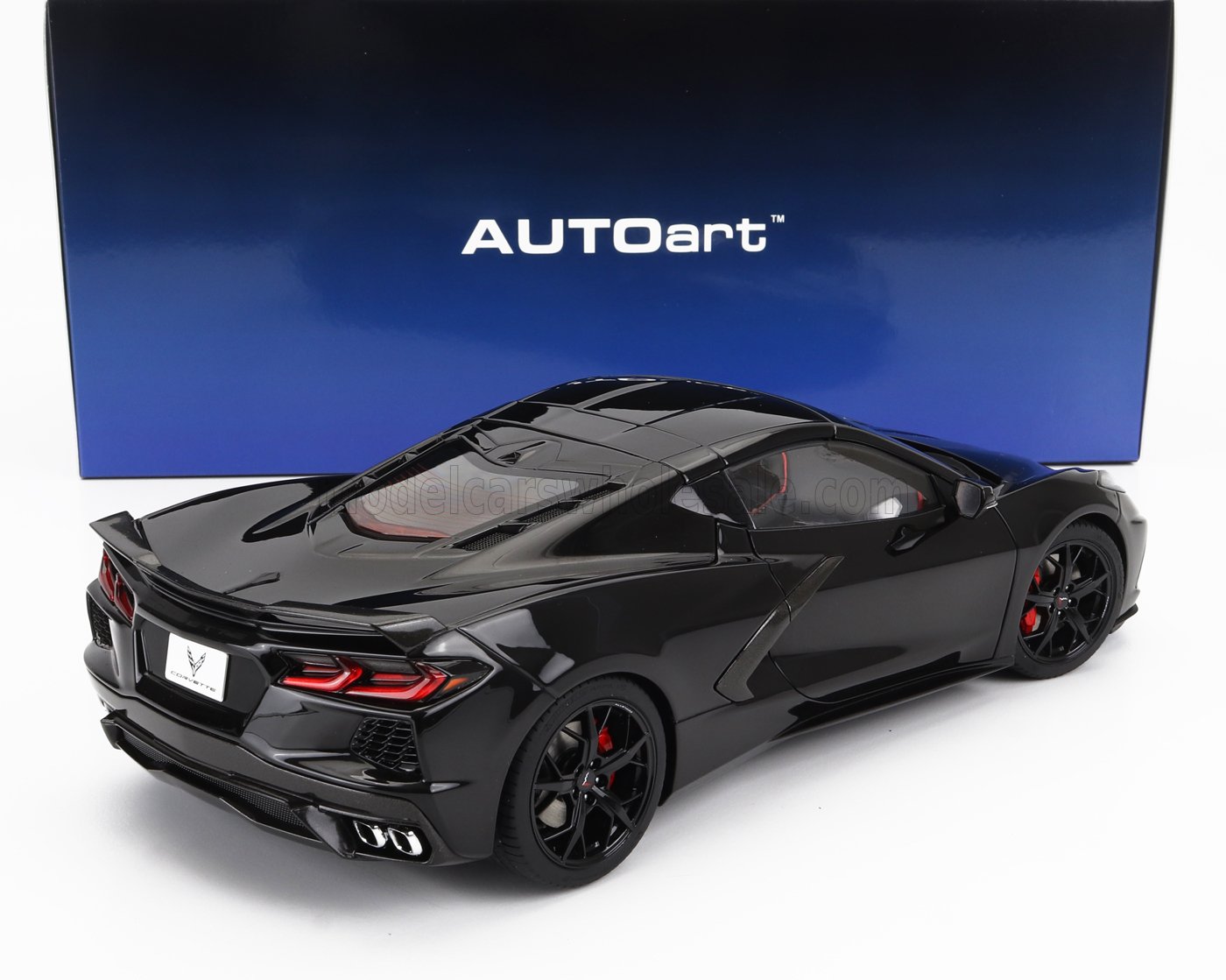 Modellino in scala nero di un'auto sportiva Chevrolet Corvette con freni rossi ben fatti, esposto davanti a una scatola AUTOart, disponibile anche sulla piattaforma Vroomi.
