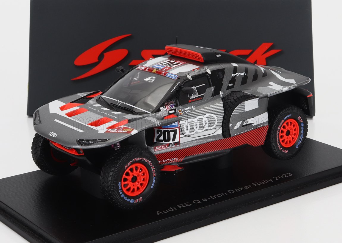 Modellino dell'Audi RS Q e-tron Dakar Rally 2023 con ruote rosse e livrea nero-grigia, disponibile su Vroomi.