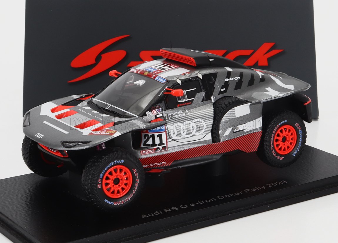 Modellino dell'Audi RS Q e-tron Dakar Rally 2023 con ruote rosse, livrea grigia e nera, disponibile su Vroomi.