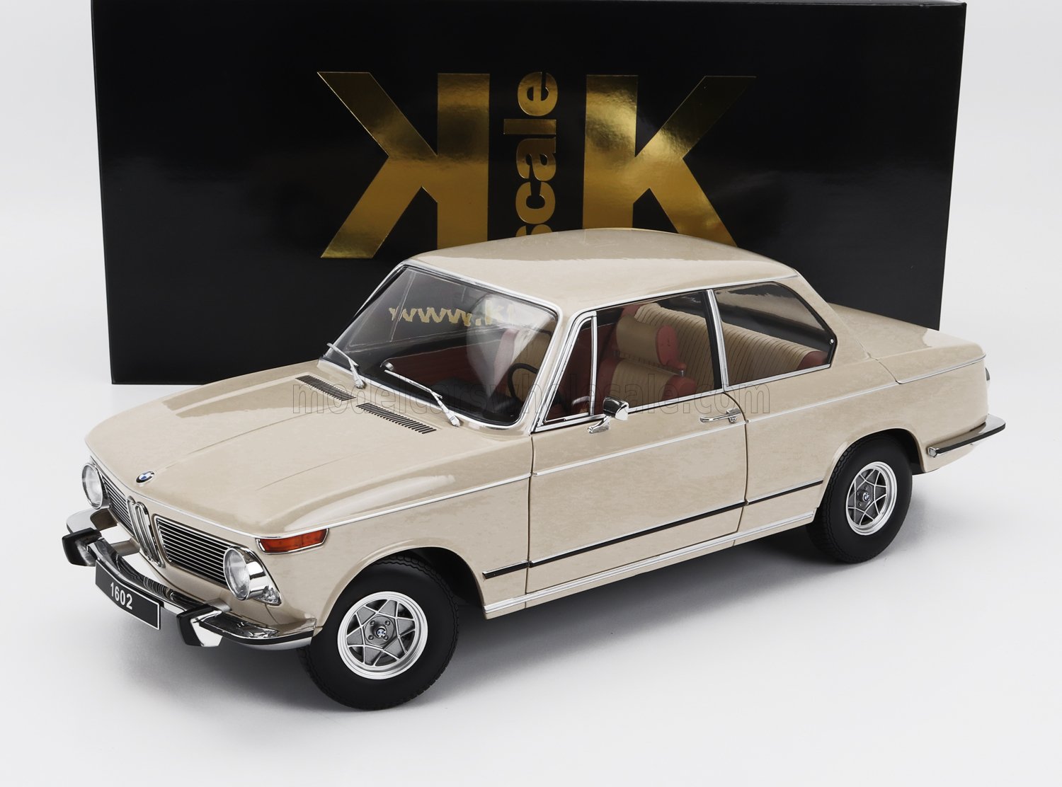 Modellino classico BMW 1602 beige con dettagli cromati, esposto davanti a una scatola KK nera e dorata, disponibile su Vroomi.