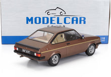 Modellino in scala 1:18 della Ford Escort marrone con striscia gialla, disponibile su Vroomi.