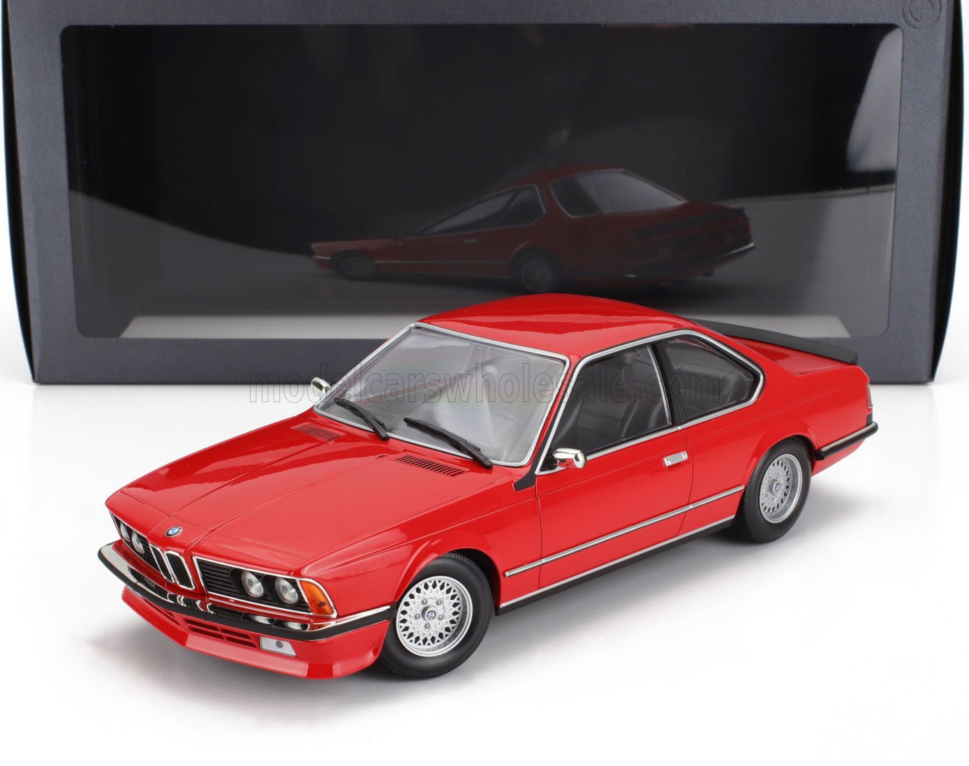 Modellino classico di BMW Serie 6 rossa con ruote super dettagliate, esposto davanti a una scatola nera, disponibile su Vroomi.