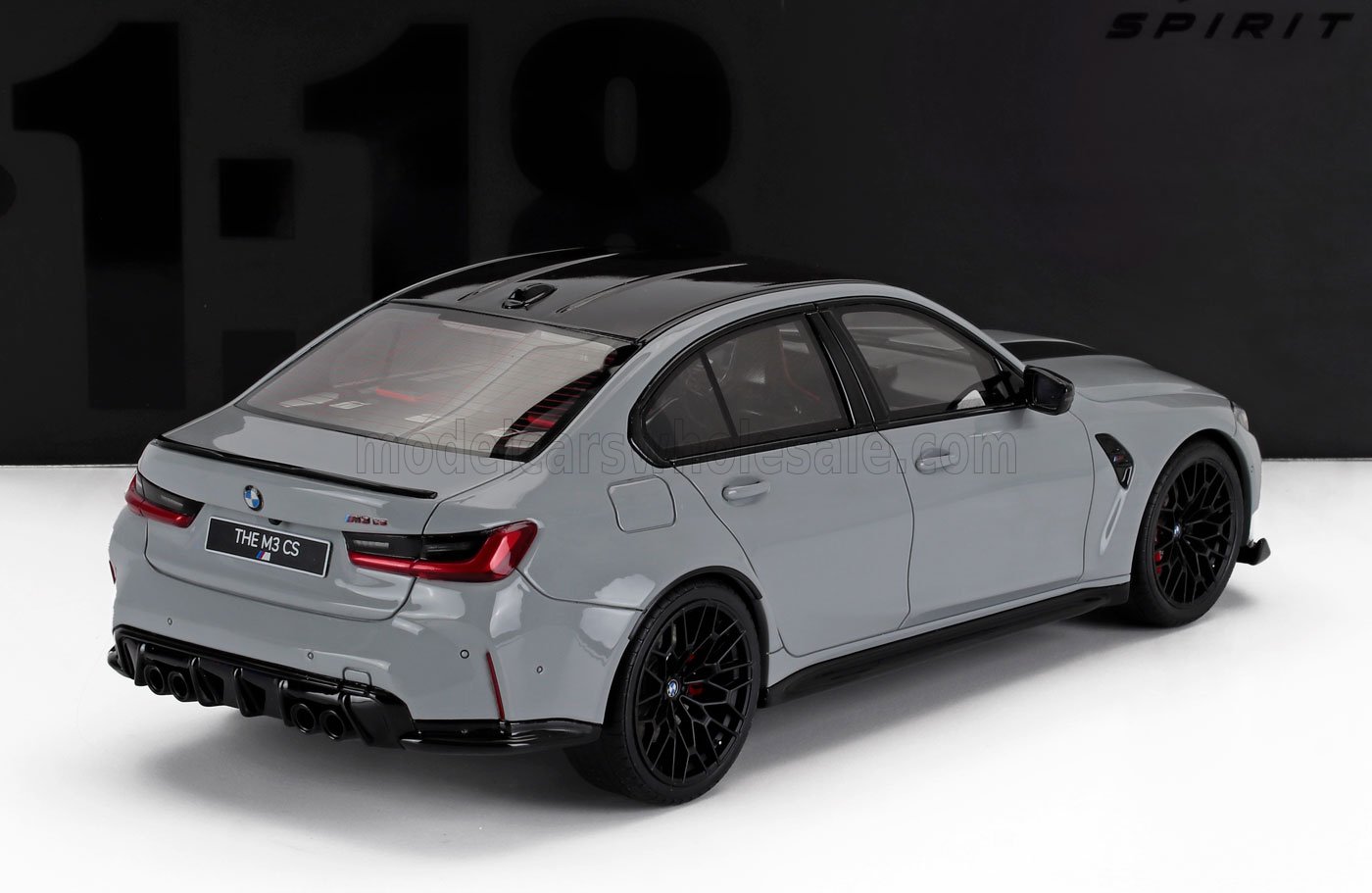 Modellino di BMW M3 CS grigio in scala 1/18 con ruote nere, esposto su una superficie bianca, disponibile su Vroomi.