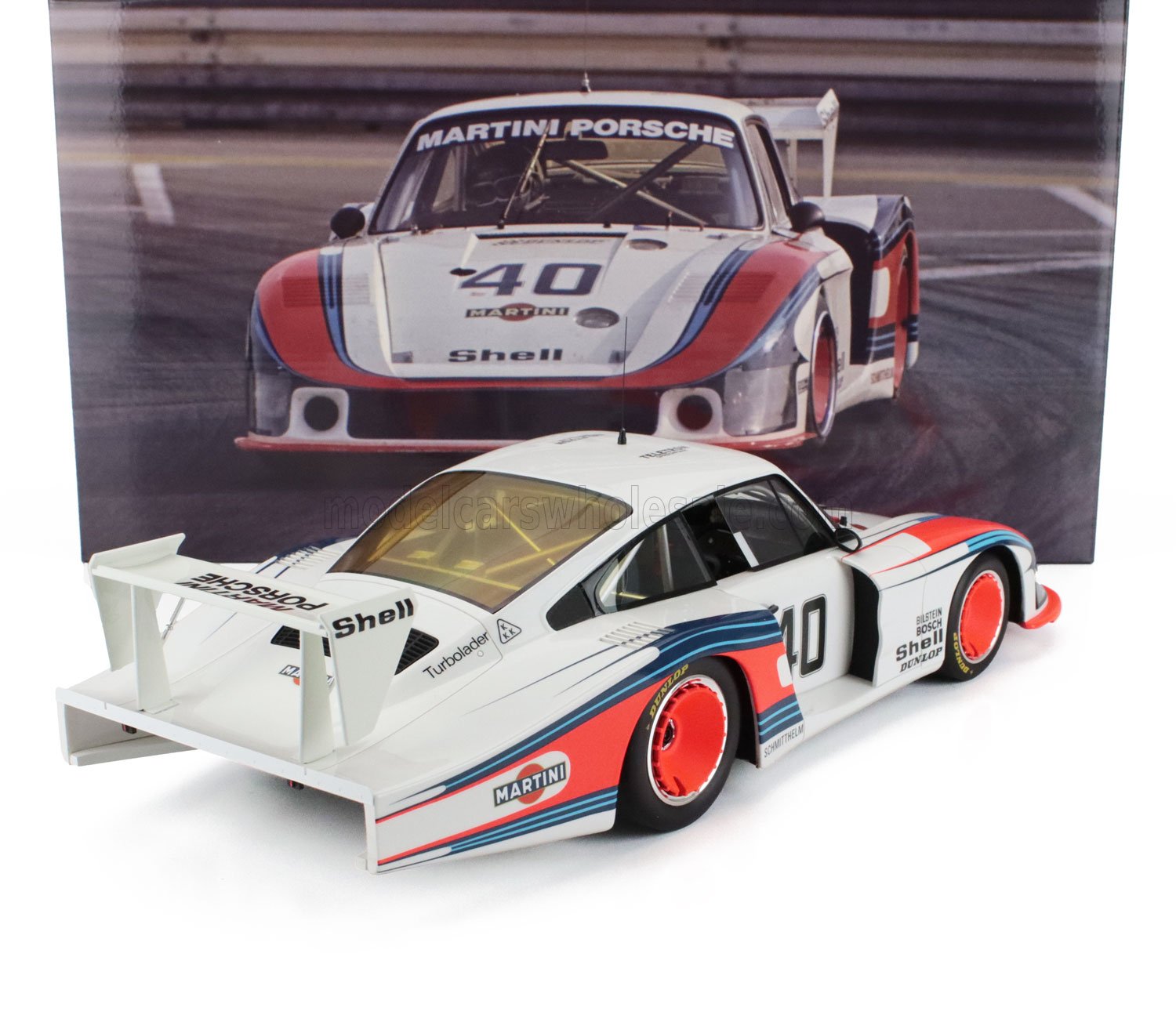 Modellino dell'auto da corsa Porsche 935 Martini in scala 1:18 con strisce rosse e blu su fondo bianco, disponibile su Vroomi.