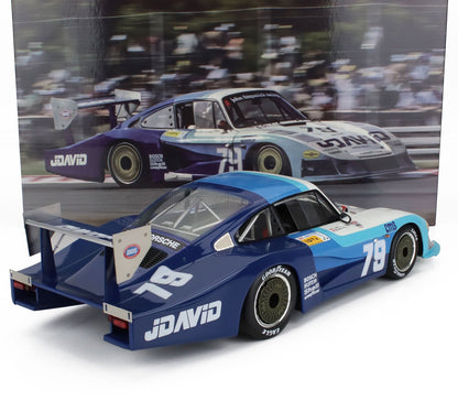 Modellino dell'auto da corsa Porsche 935 JDavid blu e bianca con il numero 79, mostrato con un poster di gara, disponibile su Vroomi.