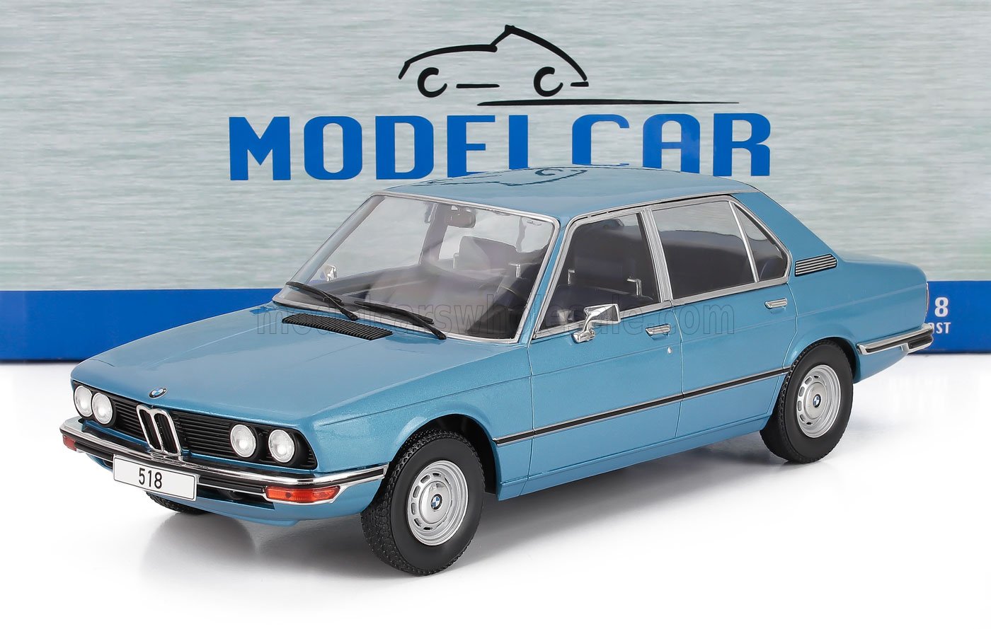 Modellino di BMW 518 blu in scala 1/18 con esterni super dettagliati, esposto su una superficie bianca, disponibile su Vroomi.