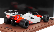 Modellino in scala di un'auto da corsa McLaren vintage con livrea rossa e bianca, dettagliata su una base marrone, disponibile su Vroomi.