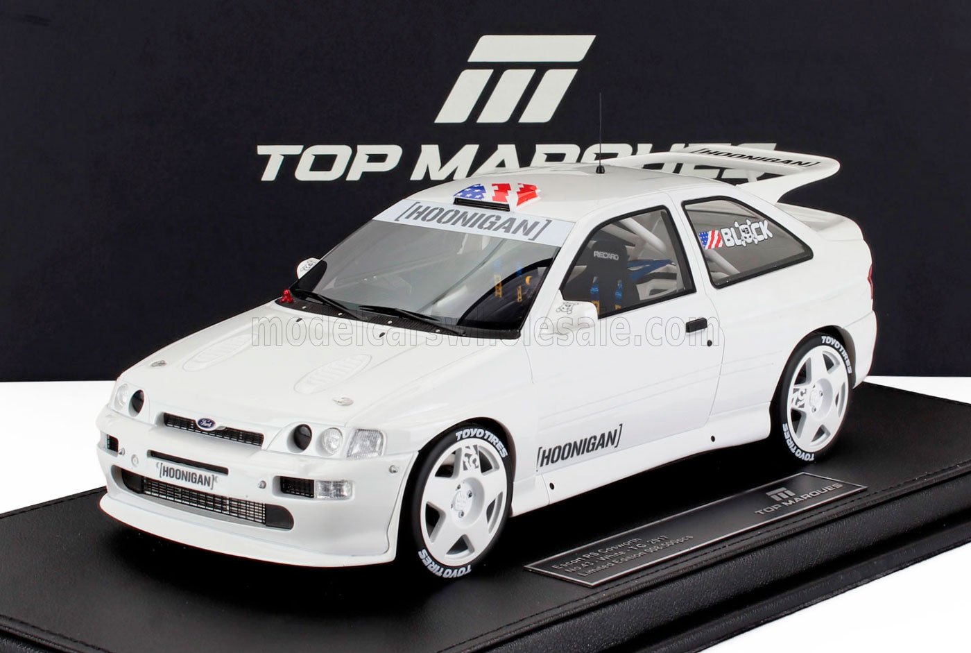 Modellino di Ford Escort RS Cosworth bianca con adesivi Hoonigan su espositore Top Marques nero, in vendita su Vroomi.