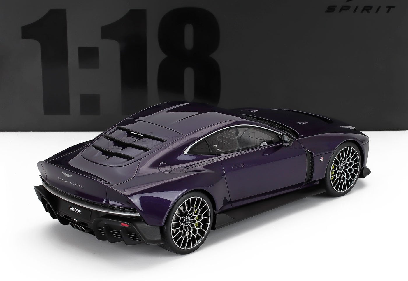Modellino Aston Martin Valour in scala 1:18, in metallo pressofuso, colore viola metallizzato con cerchi dettagliati, visto dal retro, disponibile su Vroomi.