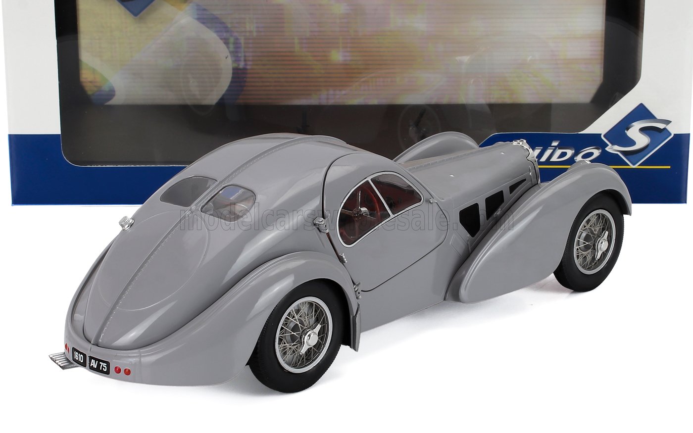 Modellino d'auto vintage grigio con curve eleganti e ruote a raggi, disponibile sulla piattaforma Vroomi.