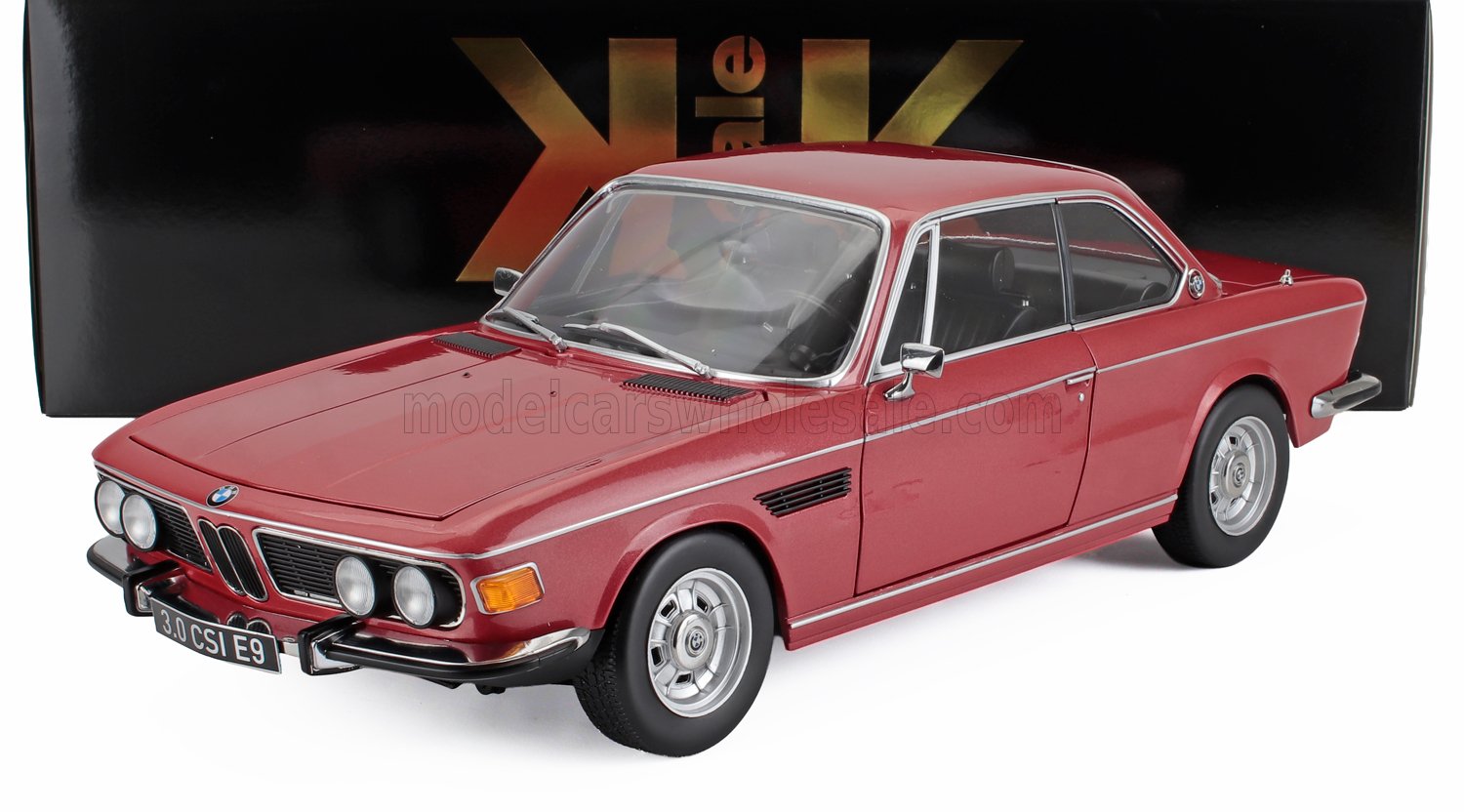 Modellino classico BMW 3.0 CSI E9 rosso con dettagli cromati, mostrato con scatola espositiva nera, disponibile tramite Vroomi.
