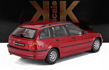 Modellino di auto BMW Serie 3 E46 station wagon rossa su superficie bianca con sfondo scuro, disponibile su Vroomi